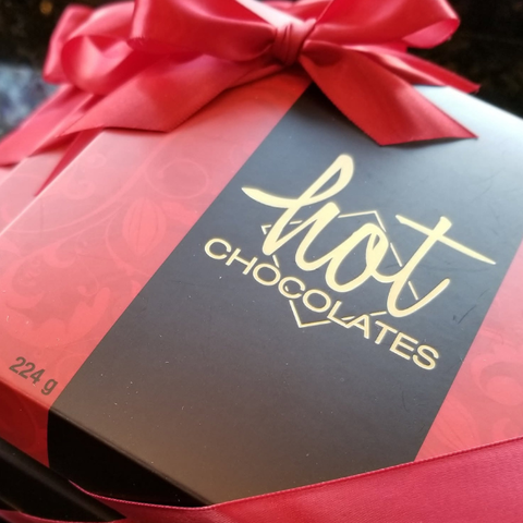 Beautiful red and brown boxes with red ribbon bows and a gold Hot Chocolates logo in the middle