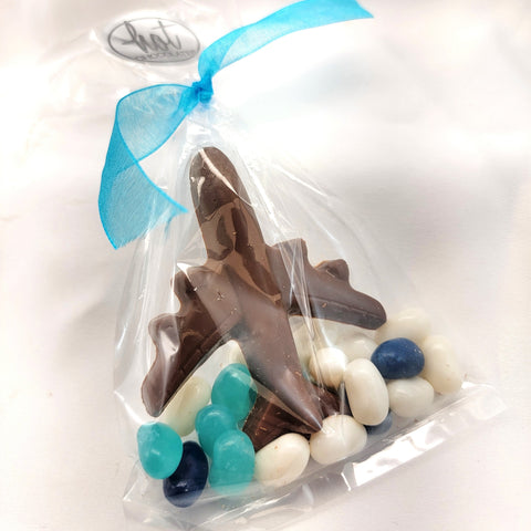 A clear cellophane treat bag tied with a light blue ribbon, containing a chocolate airplane surrounded by white, teal, and blue jelly beans on a white background.