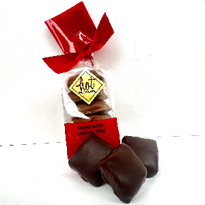 A clear cellophane bag of chocolate candies tied with a red ribbon and red label, with three chocolate covered  pieces placed in front on a white background.