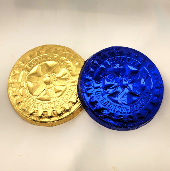 Two round foil-wrapped Rotary chocolate coins on a plain light background, one wrapped in metallic gold foil and the other in metallic blue foil, both with embossed cross-like designs and text around the edge.