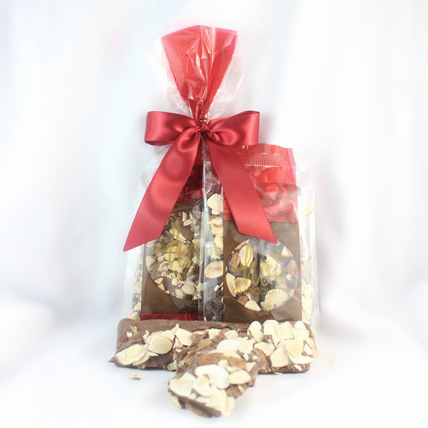 Packaged artisan chocolate dipped buttercrunch covered sliced almonds in clear plastic bags with a red ribbon.