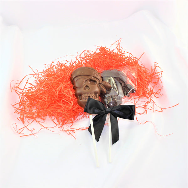 A Chocolate Pirate Lollipop Sucker designed to look like a skull, with a black bow and orange shred around it.