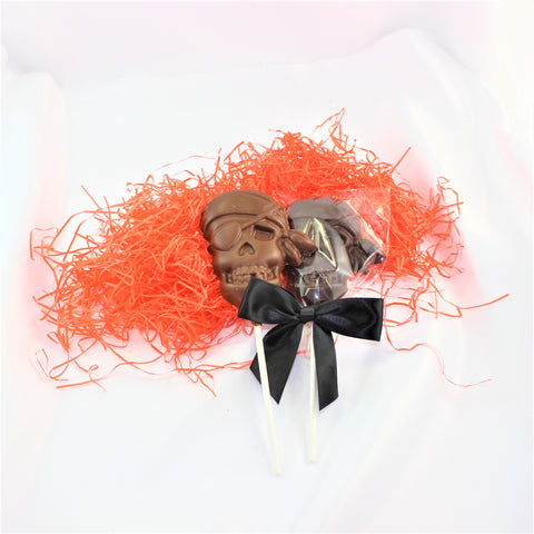 A Chocolate Pirate Lollipop Sucker designed to look like a skull, with a black bow and orange shred around it.