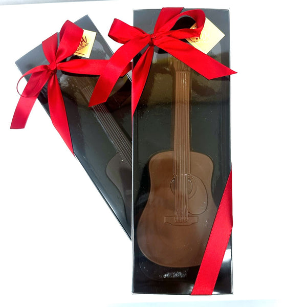 A gourmet chocolate guitar gift wrapped in black box with red ribbon bows.