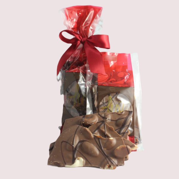 Packaged artisan chocolate deluxe nut bark in the back, with an un-bagged example foreground with a white background.