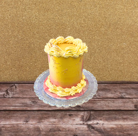 A yellow and pink No Gluten Added & Dairy-Free Tropical Cake made with mango, lime and coconut, with decorative frosting on a wooden surface.