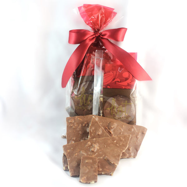 A clear plastic package containing pieces of milk chocolate bark mulch with nuts and coconut, tied with a red ribbon.