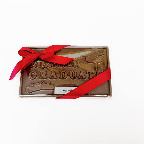 A 'Congratulations Graduate' Oat Milk Chocolate Bar gift wrapped in clear packaging and finished with a pretty, red bow on a white background.