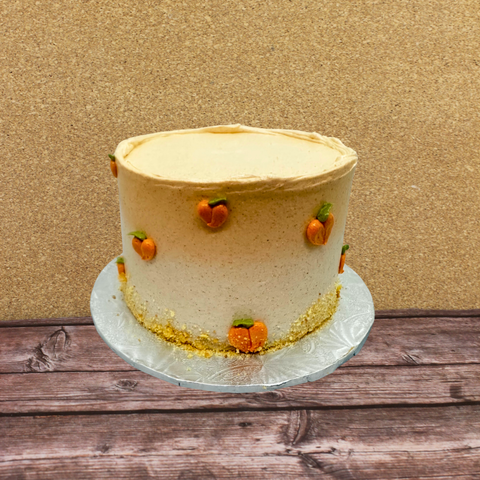 A no gluten added & dairy free seasonal cake with little peach decorations and ombre icing on a silver disk.