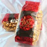 2 red and brown bags full of chili caramel popcorn on a white background.