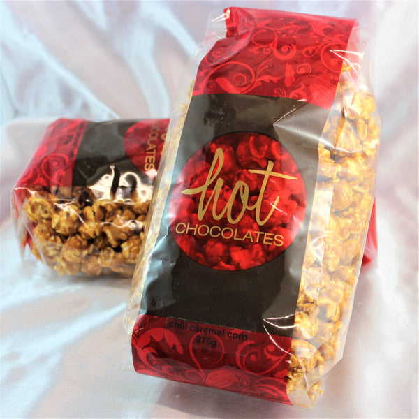 2 red and brown bags full of chili caramel popcorn on a white background.