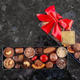 A medium box of fruits and nuts dipped in chocolate, finished with a red bow and gold Hot Chocolates logo sticker.