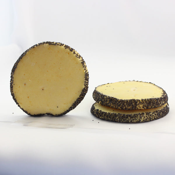 A photo showing a lemon lovers shortbread cookie rolled in poppy seeds, with a second cookie stack in the background.