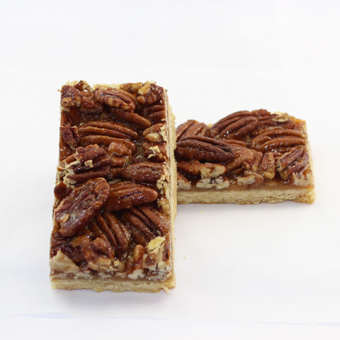 2 slices of caramel pecan shortbread bar on a white background.