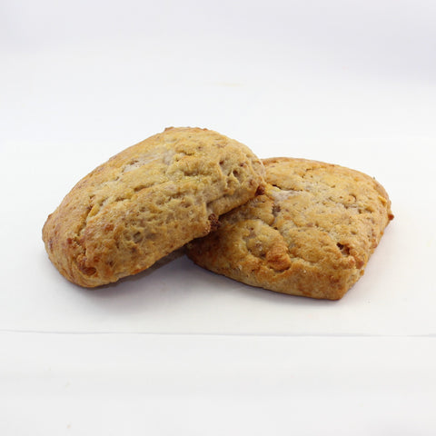 Two fresh baked sweet scones on a white background, with a golden brown crust and visible fruit and nut ingredients.