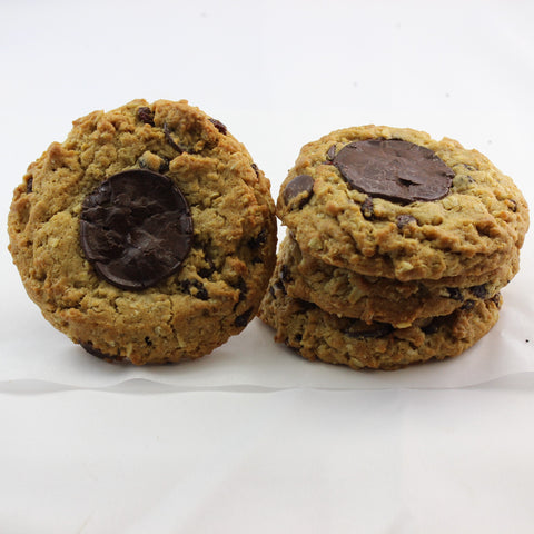 A stack of the ultimate gourmet cookie, with a single beside the stack, each cookie has a melted chocolate disc on top.