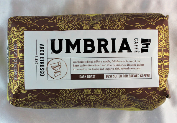 A brown bag with gold highlights filled with dark roast coffee beans from Caffe Umbria, labeled 'best for brewed coffee'.