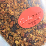 A close up of Cakebread Artisan Bakery labeled house granola in 908g, showing roasted seeds, nuts, fruit and grains.