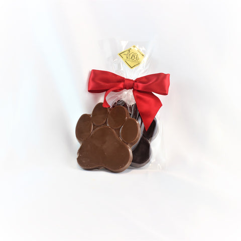 A solid chocolate paw print wrapped in clear packaging with a red ribbon.