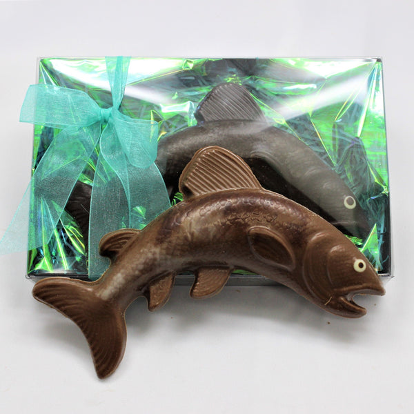 A hand painted chocolate salmon, packaged in clear wrapping with a blue ribbon.