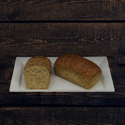 2 loaves of healthy multigrain sandwich bread called Farmers Multigrain on a white plate, displaying the textured interior and exterior of the bread with visible seeds and grains.