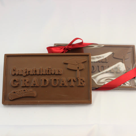 2 solid chocolate gift bars that read ' Congratulations Graduate', finished in clear packaging with a red bow on a white background.