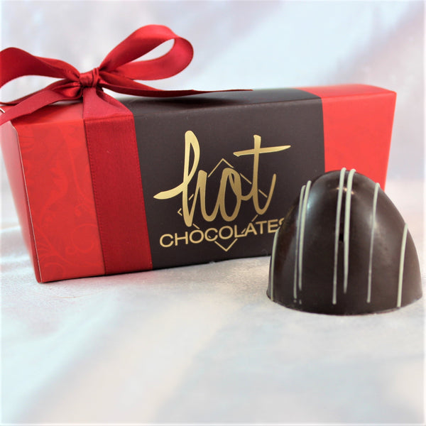 A grande margarita chocolate bonbon with a dark and white striped exterior, presented in a red box with a gold Hot Chocolates logo on the front.
