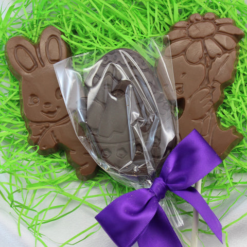 A medium chocolate Easter sucker with a decorative purple bow and packaging that resembles a bunny, set against a green and purple themed background.
