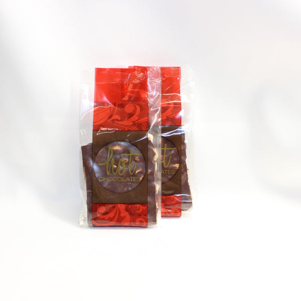 2 bags with artisan oat milk chocolate almond bark, packaged in red and brown bags with the brand 'Hot Chocolate' visible on the labels.