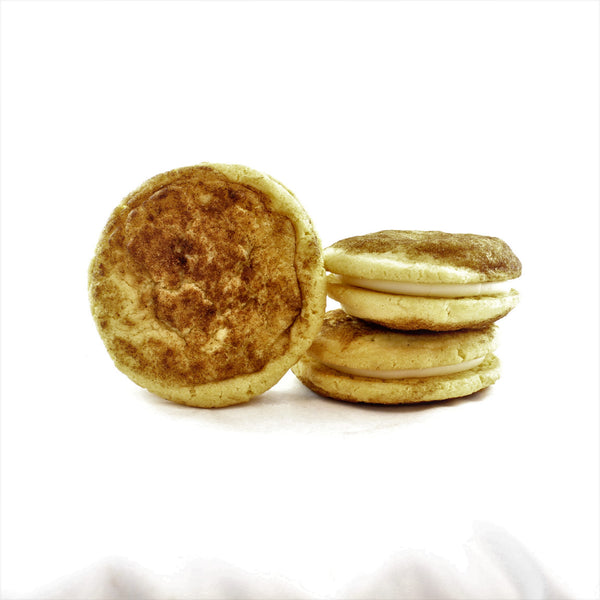 Three chewy snickerdoodle sandwich cookies with cream cheese frosting, stacked on top of each other, with one beside the stack.