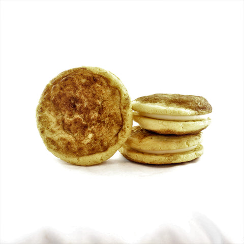 Three chewy snickerdoodle sandwich cookies with cream cheese frosting, stacked on top of each other, with one beside the stack.